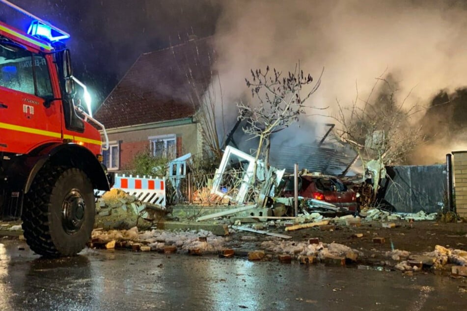 Ein Einsatzfahrzeug der Feuerwehr steht vor einer zerstörten Doppelhaushälfte in Finsterwalde.