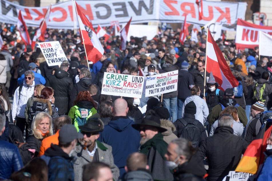 Demonstranten halten bei einer Kundgebung gegen die Coronamaßnahmen-Maßnahmen der österreichischen Bundesregierung Schilder in die Höhe.