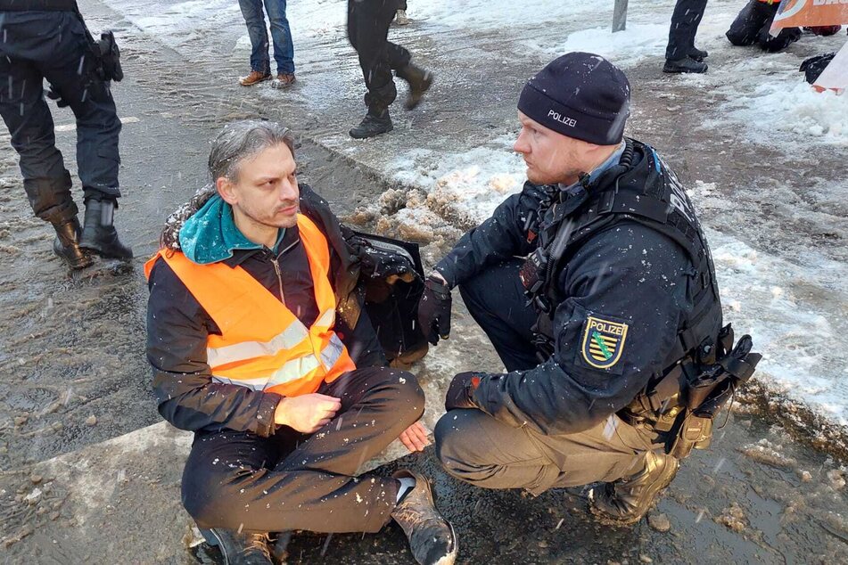 Ein Polizist im Gespräch mit einem Aktivisten, der sich auf dem Georgiring festgeklebt hat.