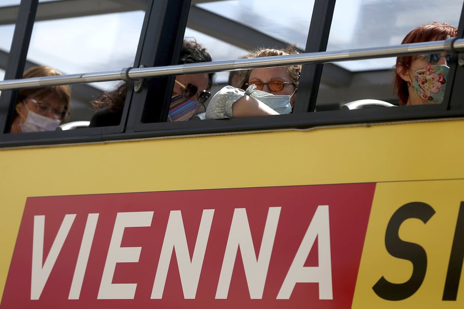Menschen sitzen in einem Wiener Touristenbus und tragen Gesichtsmasken