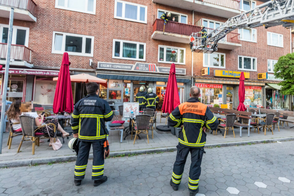 Einsatzkräfte begutachten den bröckelnden Balkon über der Terrasse des Eis-Cafés.