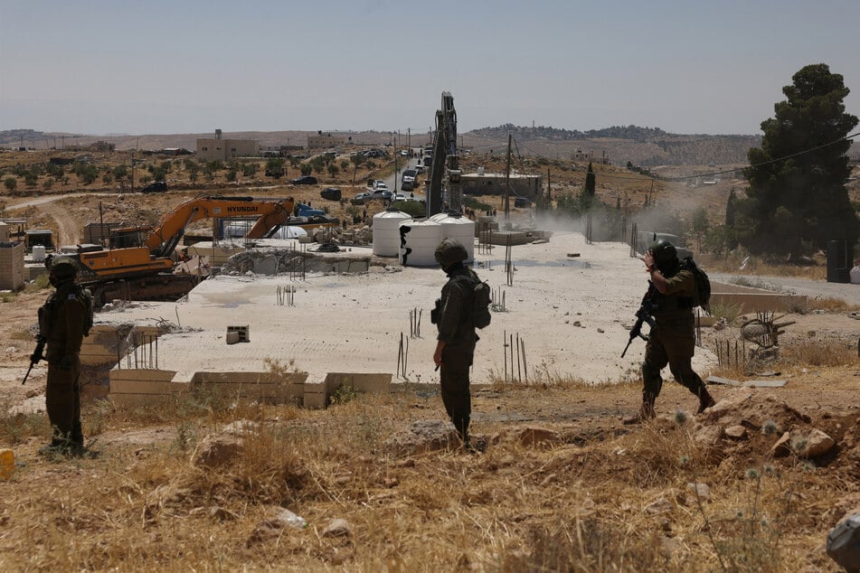 Israeli security forces guard bulldozers as they demolish a Palestinian home near the Israeli-occupied West Bank city of Hebron on June 17, 2026.