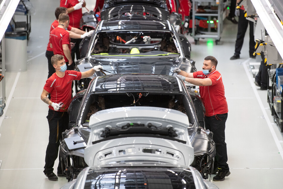 Stuttgart: Mitarbeiter der Porsche AG tragen bei der Produktion des elektrisch angetriebenen Sportwagens Porsche Taycan Mundschutz.