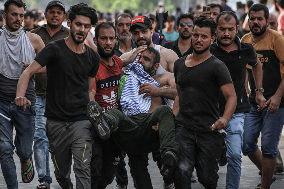 Demonstranten bringen einen verletzten Mann in Sicherheit.