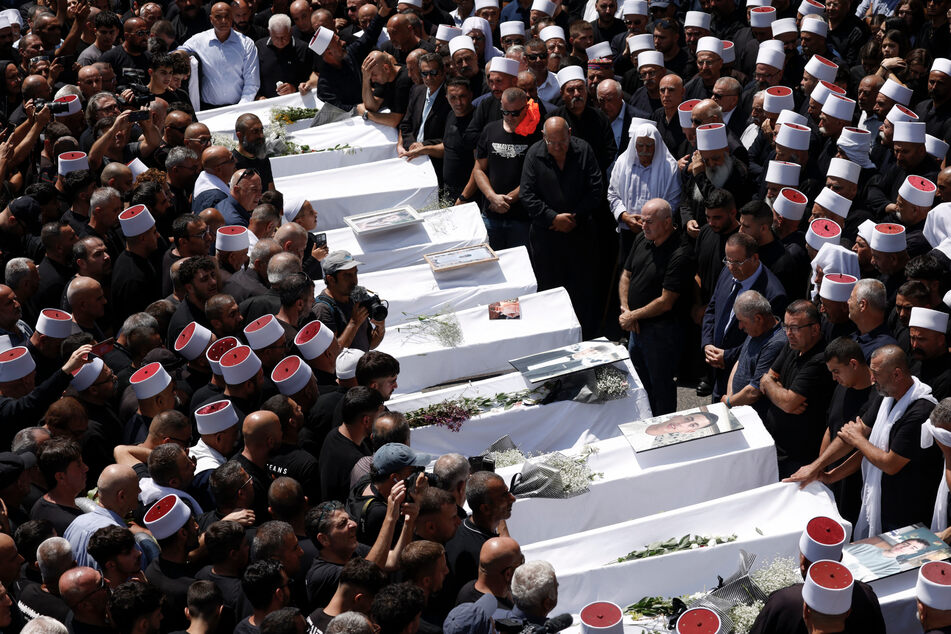 Druze elders and mourners surround the coffins of 10 of the 12 people killed in a rocket strike from Lebanon a day earlier during a mass funeral in the Druze town of Majdal Shams in the Israel-annexed Golan Heights on Sunday.