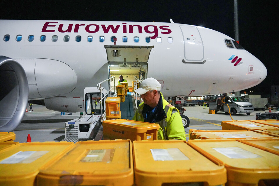 Auf dem Flughafen Berlin Brandenburg (BER) wird eines der letzten sechs Flugzeuge mit Plastikboxen voller Briefe und anderer Post beladen.