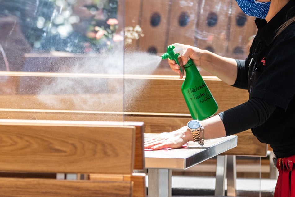 Eine Mitarbeiterin eines Restaurants in der Münzgasse reinigt die Tische, die mit Plexiglasscheiben getrennt sind, mit Desinfektionsmittel.