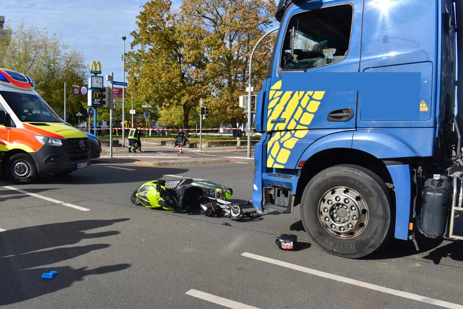 Das Motorrad des Unfallopfers liegt vor dem Laster auf der Straße, im Hintergrund ist das Absperrband der Polizei zu sehen.