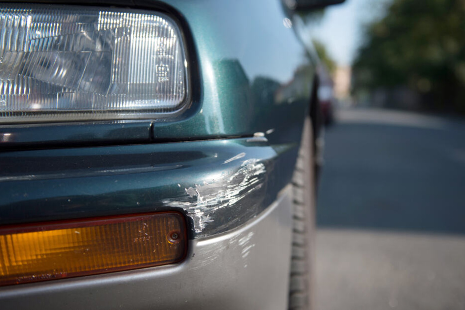 Am Stoßfänger eines geparkten Autos sind Spuren eines Unfalls zu sehen (Symbolbild).