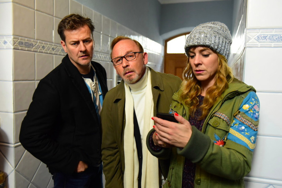 Die Kommissare Harald Neuhauser (Marcus Mittermeier, l-r), Ludwig Schaller (Alexander Held) und Angelika Flierl (Bernadette Heerwagen) begutachten die Leiche im Flur eines Hauses in Giesing in einer Szene des Films "München Mord - Ausnahmezustand".