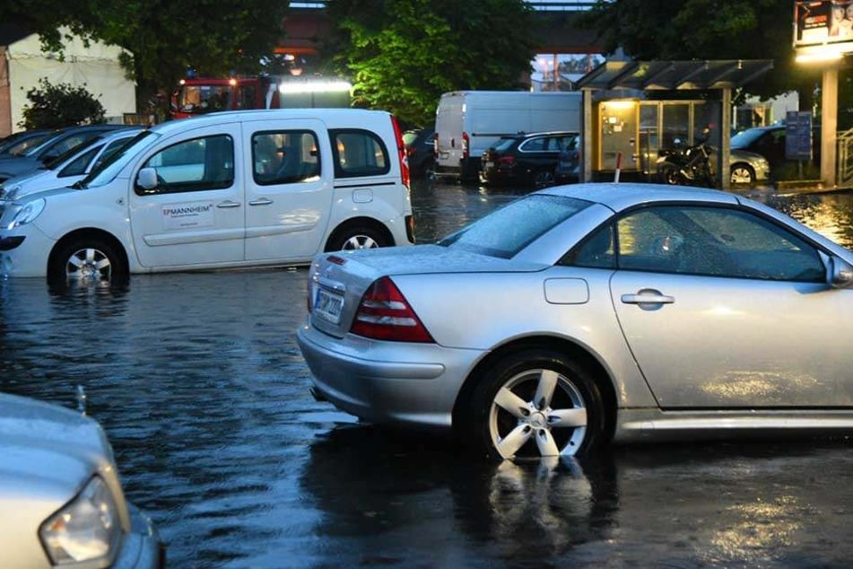 Nach einem schweren Gewitter mit Starkregen stehen Autos auf einem teilweise überflutetem Parkplatz in Mannheim.
