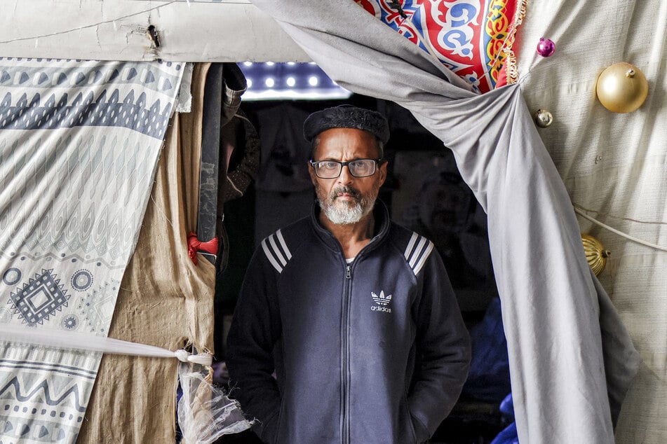 Sameer Abu Salah stands at the entrance of his tent at an encampment in Nablus Football Stadium on May 7, 2026.