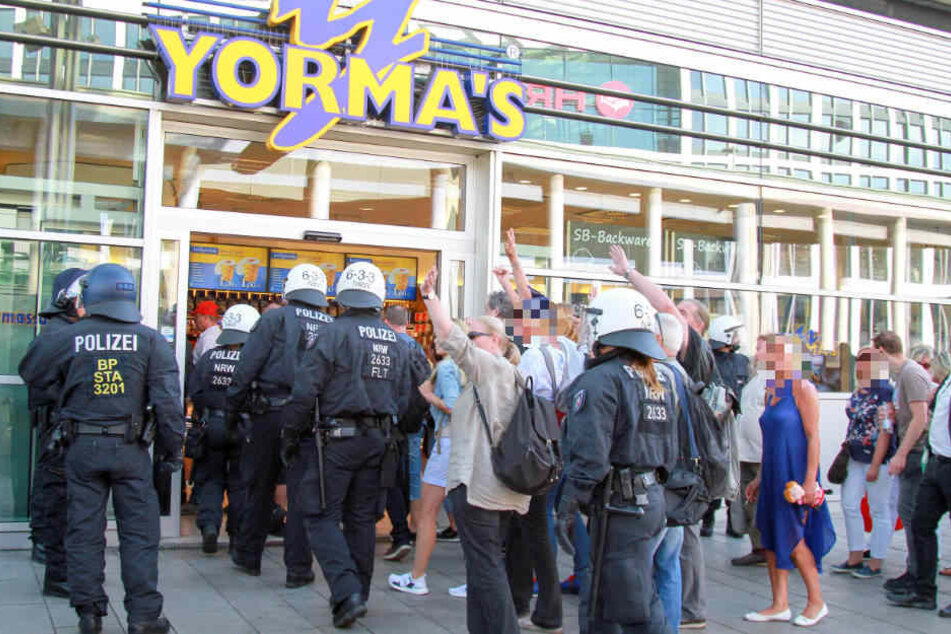 Die rechtsgerichteten Demonstranten werden durch einen Supermarkt in das Bahnhofsgebäude gelotst. Einige winken hämisch in Richtung der Gegendemonstranten.