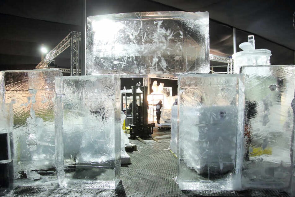 Die noch unbearbeiteten Eisblöcke stapeln sich zu einem Tor. Die ersten Umrisse erhalten sie mit der Kettensäge.