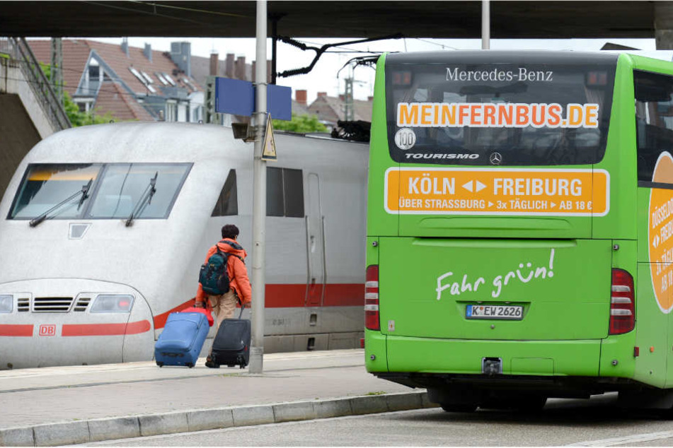 Ein Fernbus steht am Bahnhof in Freiburg (Baden-Württemberg) neben einem ICE-Zug der Deutschen Bahn.