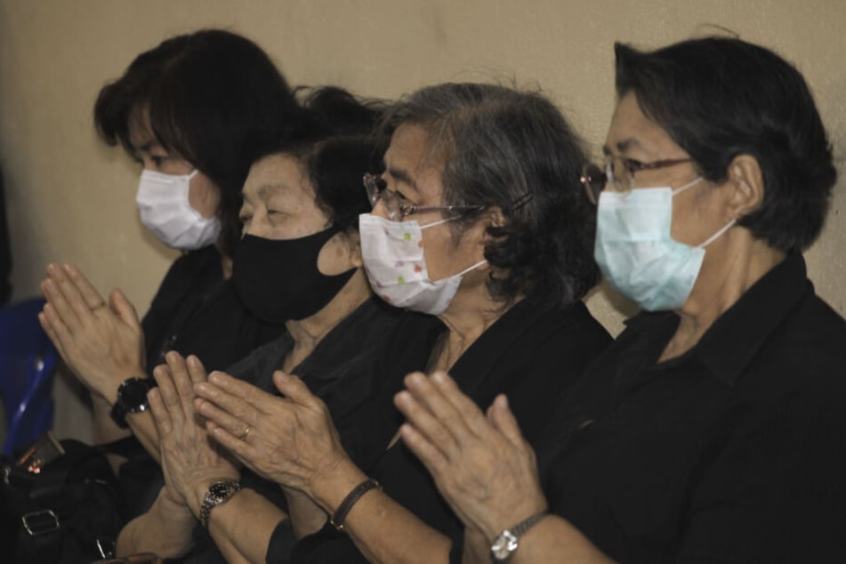 Menschen mit Gesichtsmasken nehmen an der Beerdigungszeremonie eines 35 Jahre alten Thailänders teil, der an Dengue-Fieber litt und sich später mit Covid-19 infizierte.