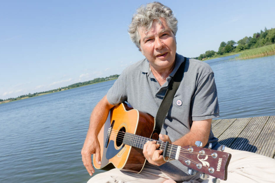 Der Autor Wolfram Eicke spielt am Dienstag auf einem Anleger am Großen Pölitzer See Gitarre.