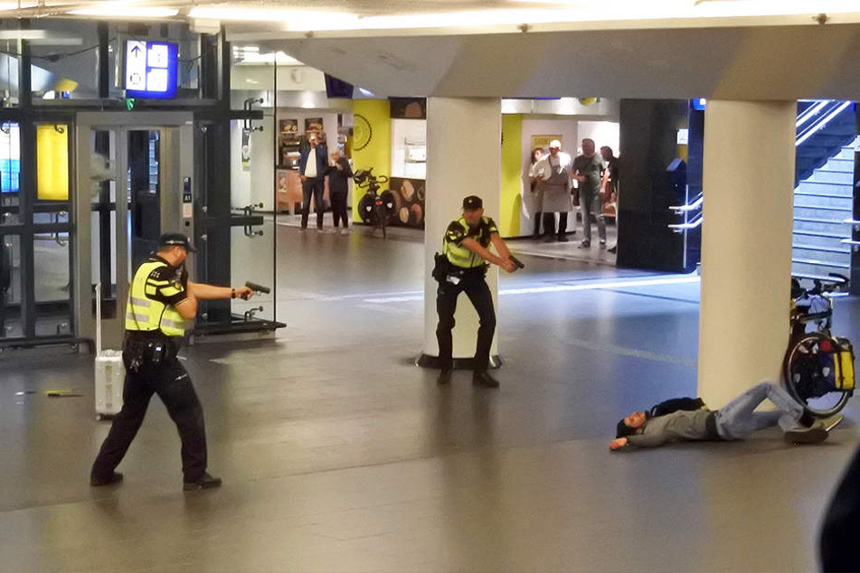 Polizisten richten die Waffe auf den Mann, den sie zuvor angeschossen haben. Er stach zuvor zwei Menschen mit einem Messer nieder.