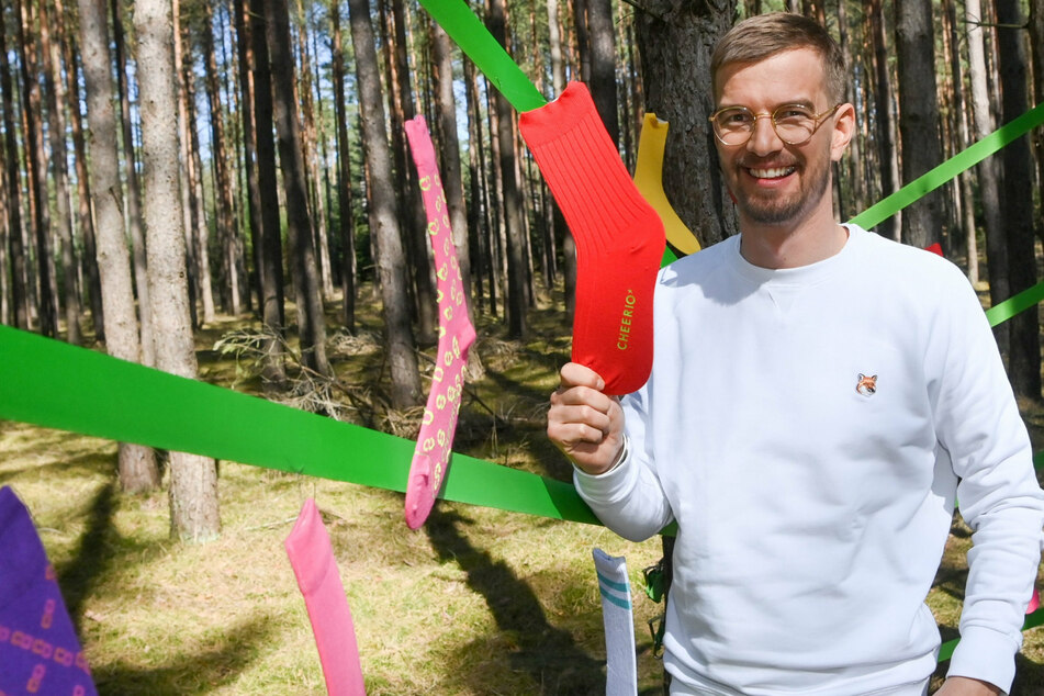 Der Entertainer und Unternehmer Joko Winterscheidt (42) steht beim Launch des neuen nachhaltigen Socken-Labels Cheerio in einem Wald bei Mirow im Landkreis Mecklenburgische Seenplatte, der mit farbigen Socken dekoriert ist.