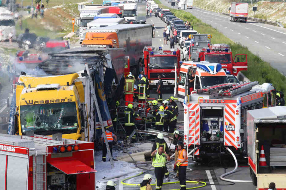 Feuerwehrleute arbeiten auf der Autobahn 9 bei Schleiz im Saale-Orla-Kreis an einem brennenden Lastwagen.