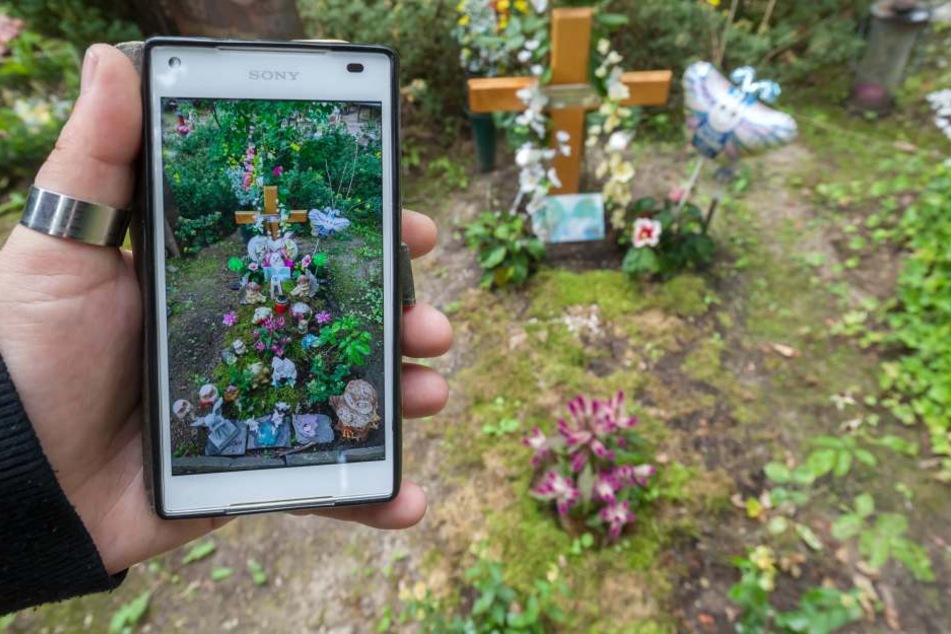 Antje Emmerlich zeigt ein Handybild, auf dem das Grab mit Blumenschmuck zu sehen ist.