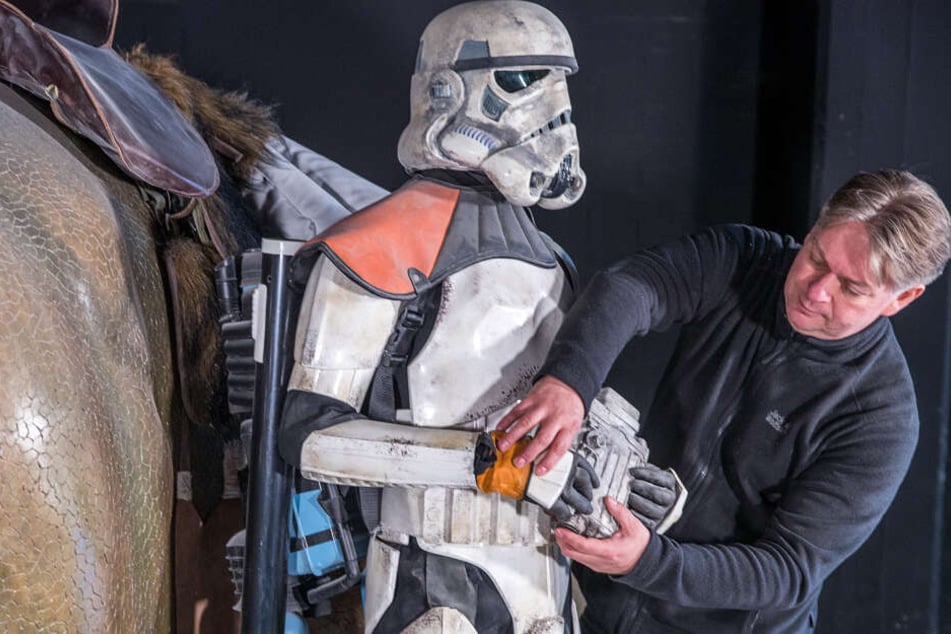 Marc Langrock, Star Wars Fan und Gründer des Museums, richtet einen Stormtrooper vor dem Reitwesen Dewback aus.
