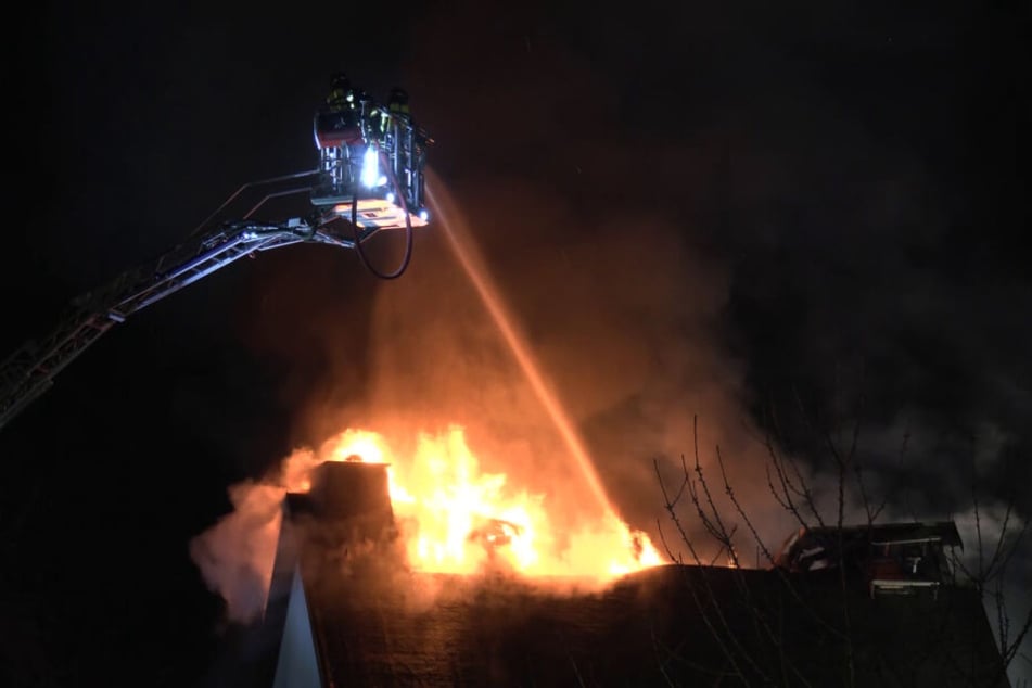 Von der Drehleiter aus versuchen Feuerwehrleute, den Hausbrand zu löschen.