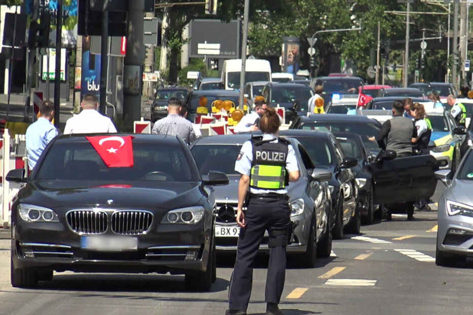 Eine Polizistin steht vor den Fahrzeugen eines türkischen Hochzeitskorsos.