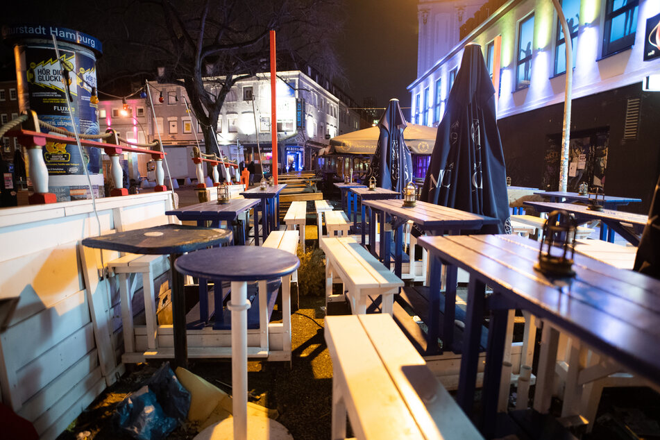 Leere Tische und Bänke stehen vor einem Club auf dem Hamburger Kiez