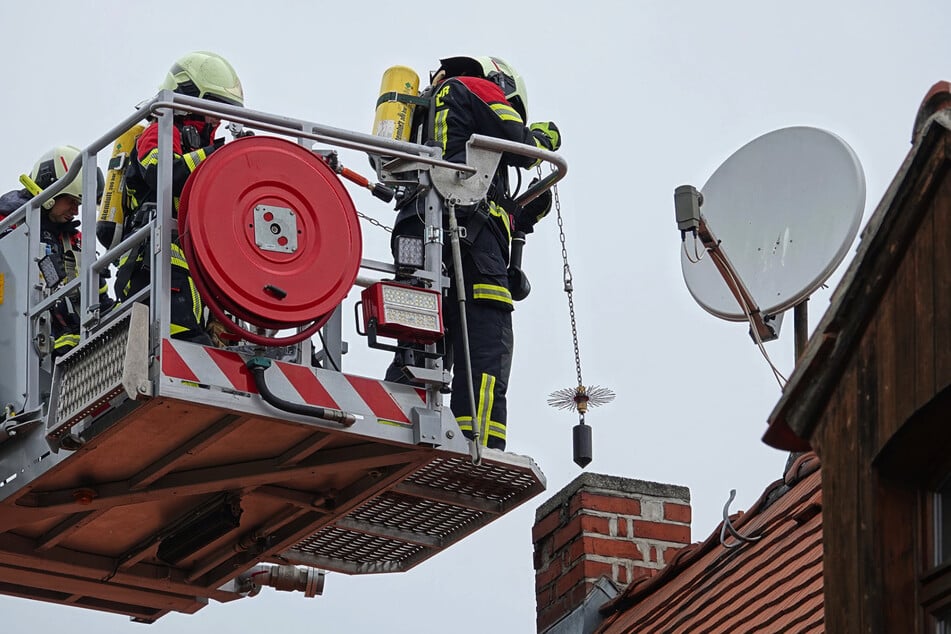 Einsatzkräfte senken das sogenannte Essenkehrgerät in den Schornstein hinab.