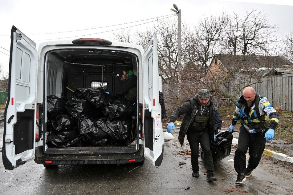 Städtische Mitarbeiter verladen in Butscha Leichen in einen Transporter.