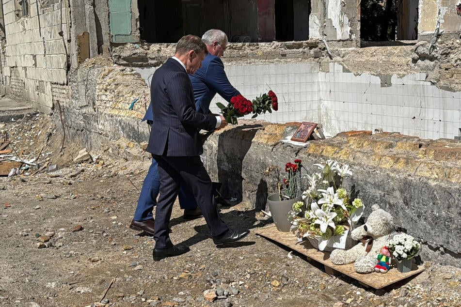 Johann Wadephul (63, CDU, l), Außenminister von Deutschland, und sein ukrainischer Amtskollege Andrij Sybiha legen Rosen nieder an einem Haus, das bei einem Raketenangriff am 17. Juni zerstört wurde.
