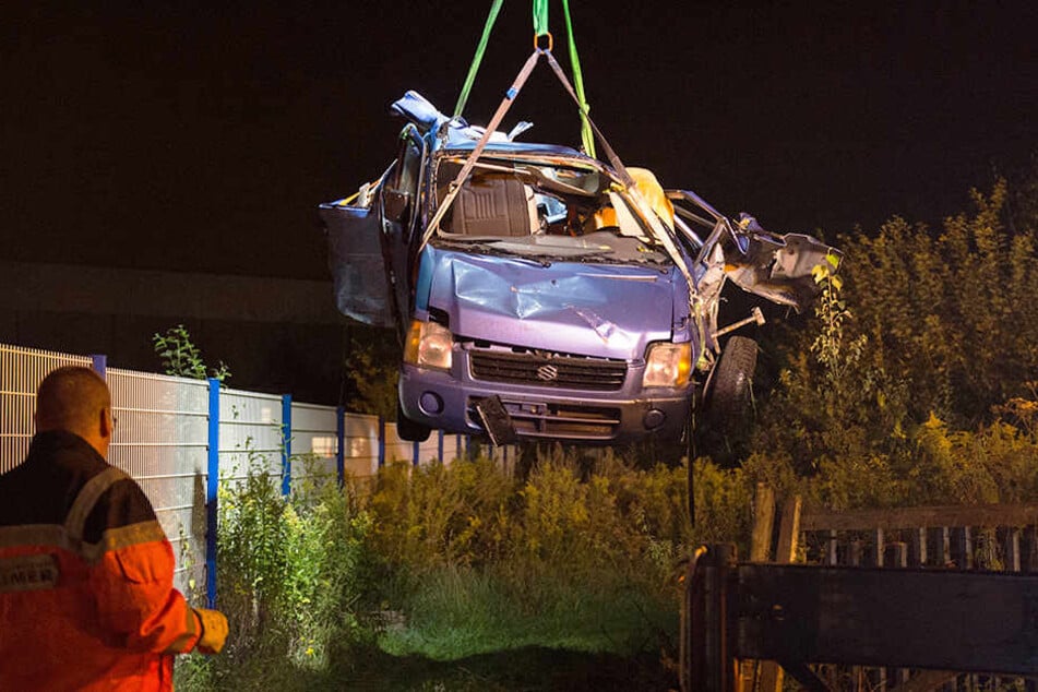 Das Fahrzeugwrack wird nach dem Zusammenstoß aus einem Gebüsch auf ein Bergungsfahrzeug gehoben.