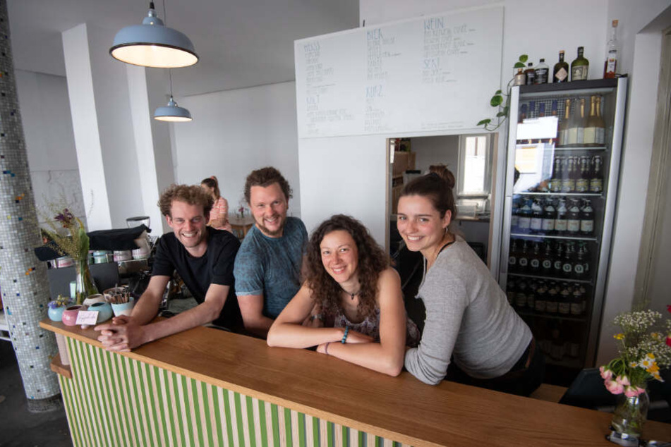 Mitglieder des Gründerteams des Café "Raupe Immersatt" stehen hinter der Theke ihres Cafés.