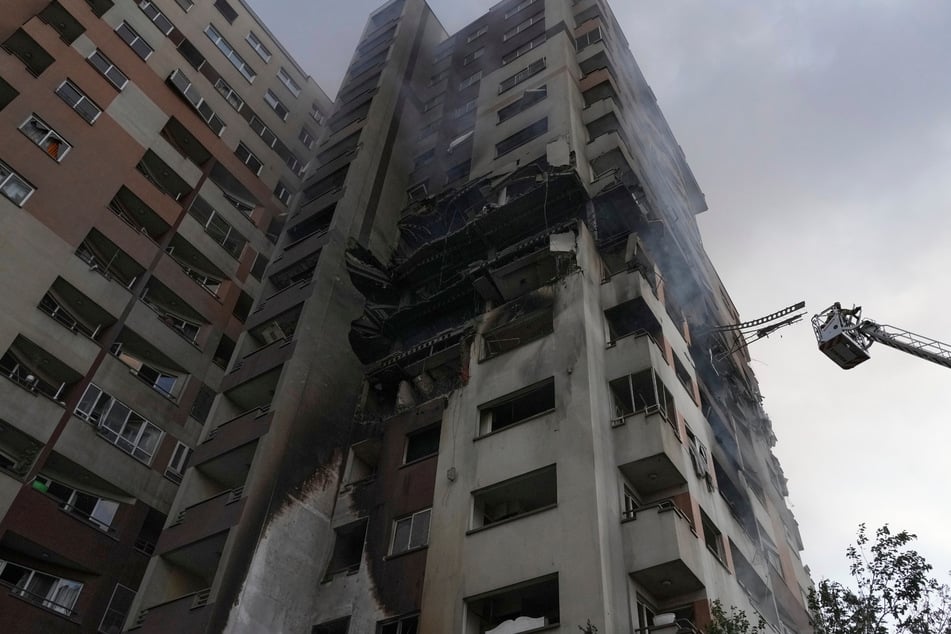 Teheran: Ein Feuerwehrmann steht auf einem Kran am Ort einer Explosion in einer Wohnanlage nach israelischen Angriffen.