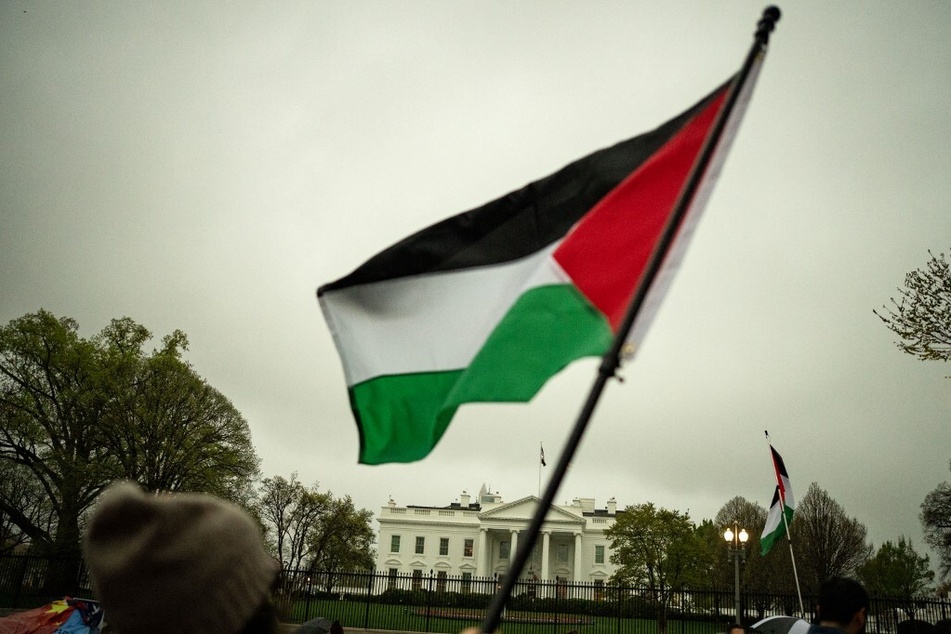 Protesters wave a Palestinian flag outside the White House demanding a permanent ceasefire in Gaza and an end to US arms transfers to Israel.