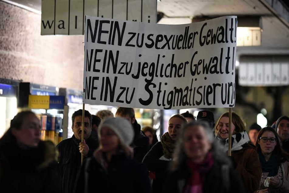 Demonstranten halten ein Plakat mit der Aufschrift "Nein zu sexueller Gewalt! Nein zu jeglicher Gewalt! Nein zu Stigmatisierung!".