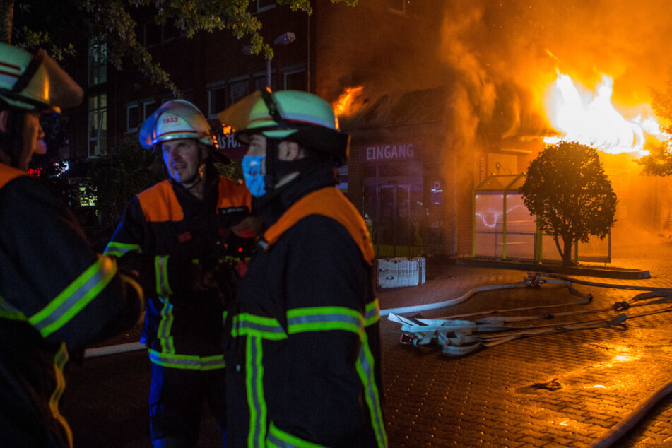 Feuerwehrleute stehen am Rande des Großbrands in einem Geschäft für Tierbedarf.