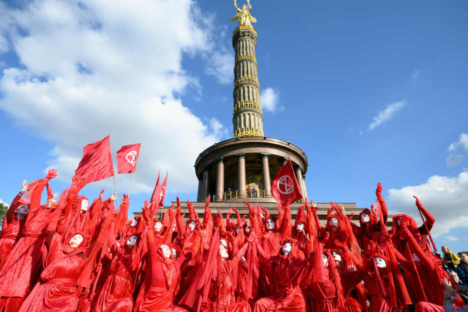 Rot gekleidete Aktivisten der Klimabewegung "Extinction Rebellion" führen zum Auftakt ihrer Aktionswoche "Berlin blockieren" bei einer Blockade der Zufahrten zum Großen Stern an der Siegessäule eine Aufführung auf.