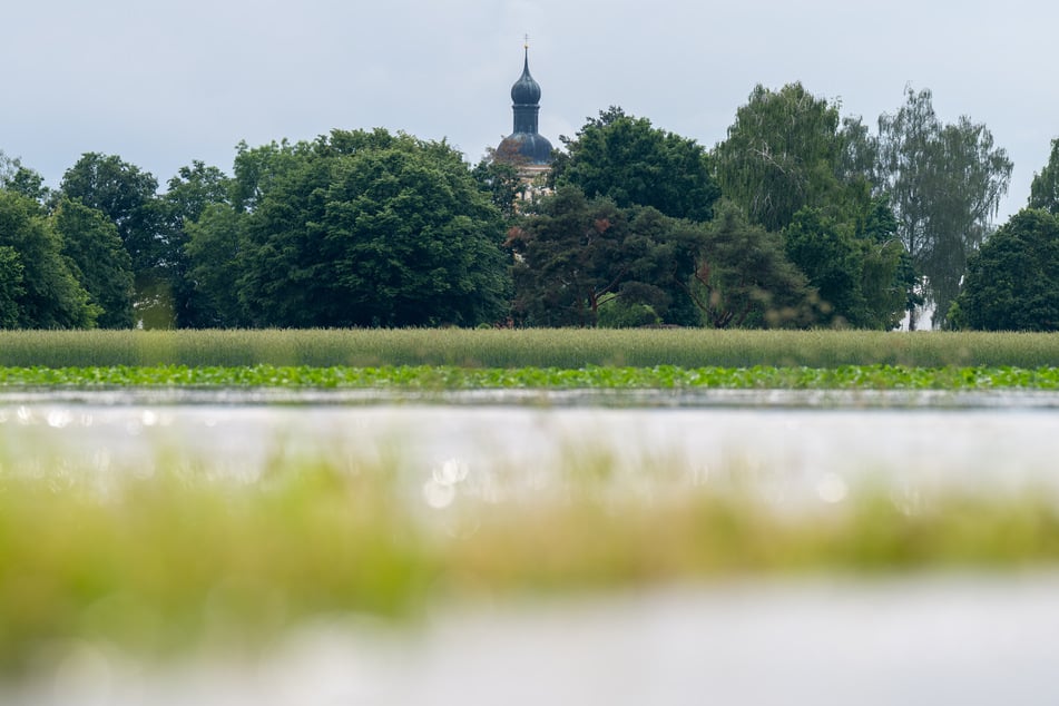 Hinter überfluteten Feldern ist der Kirchturm der Pfarrkirche St. Martin in Baar-Ebenhausen (Bayern) zu erkennen. Der Landkreis Pfaffenhofen an der Ilm ist von dem Hochwasser schwer getroffen.