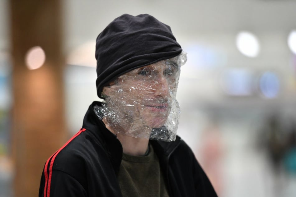 Australien, Brisbane: Ein Mann hat am Flughafen von Brisbane sein Gesicht in Plastik eingewickelt, um sich vor dem Coronavirus (COVID-19) zu schützen.