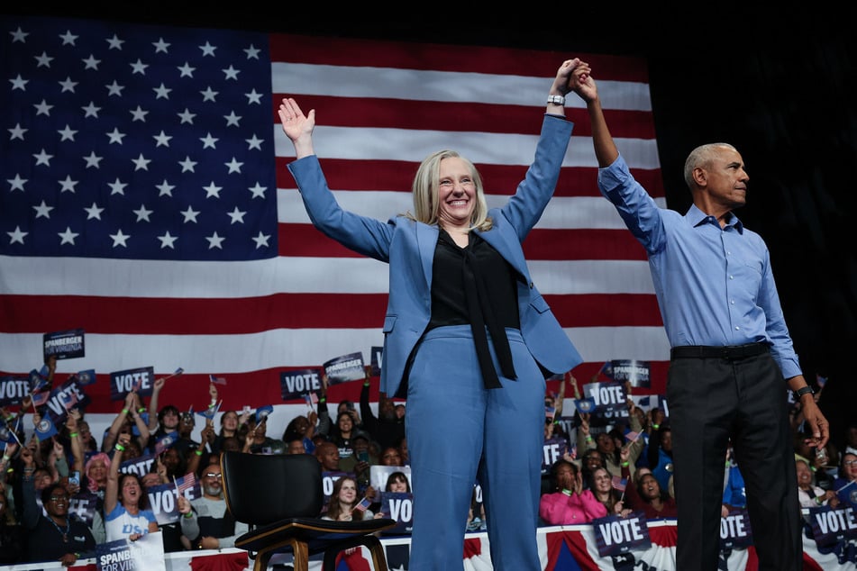 Former President Barack Obama and Virginia Democratic gubernatorial candidate Abigail Spanberger raise their arms together during a campaign rally in Norfolk on November 1, 2025.