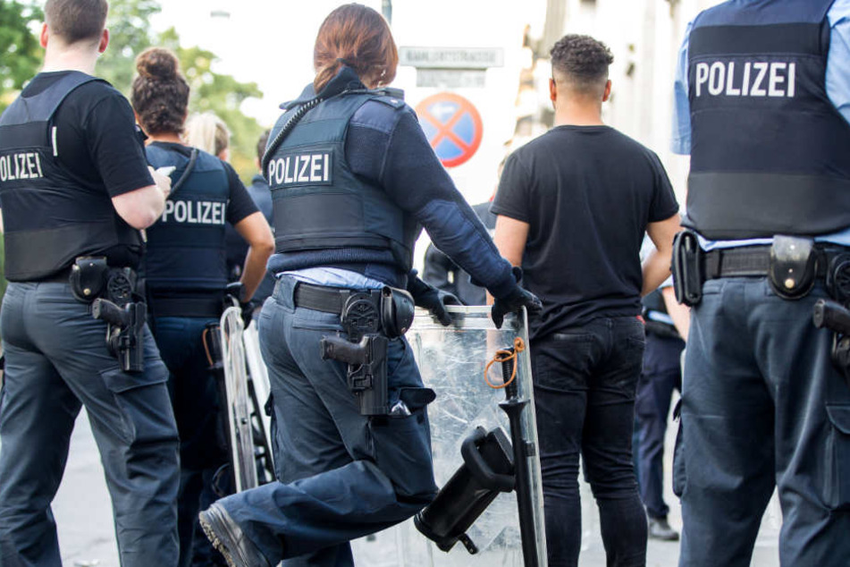 Polizisten bewachen am frühen Morgen eine Gruppe festgesetzter junger Männer neben dem Herrngarten am Rande der Innenstadt.