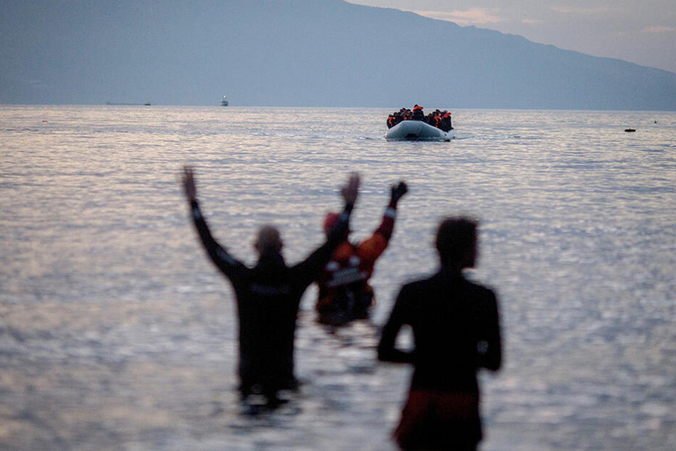 Flüchtlinge kommen in einem Schlauchboot aus der Türkei auf der griechischen Insel Lesbos in der Nähe der Hafenstadt Mitilini (Griechenland) an und werden von Helfern erwartet.