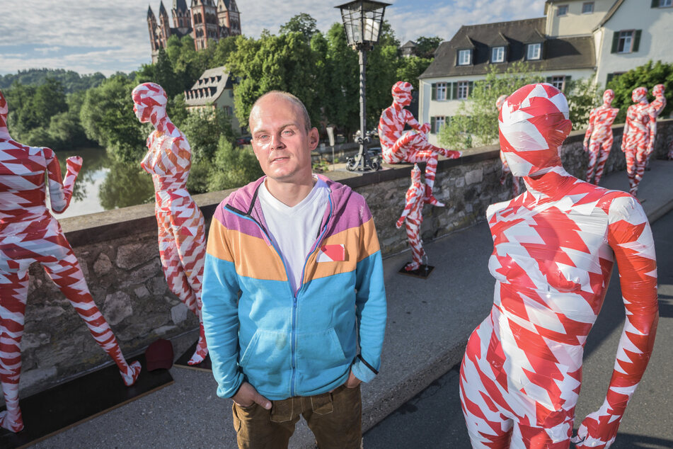 Dennis Josef Meseg, Kunststudent und Initiator der Kunstaktion, neben den Schaufensterpuppen auf der alten Lahnbrücke.