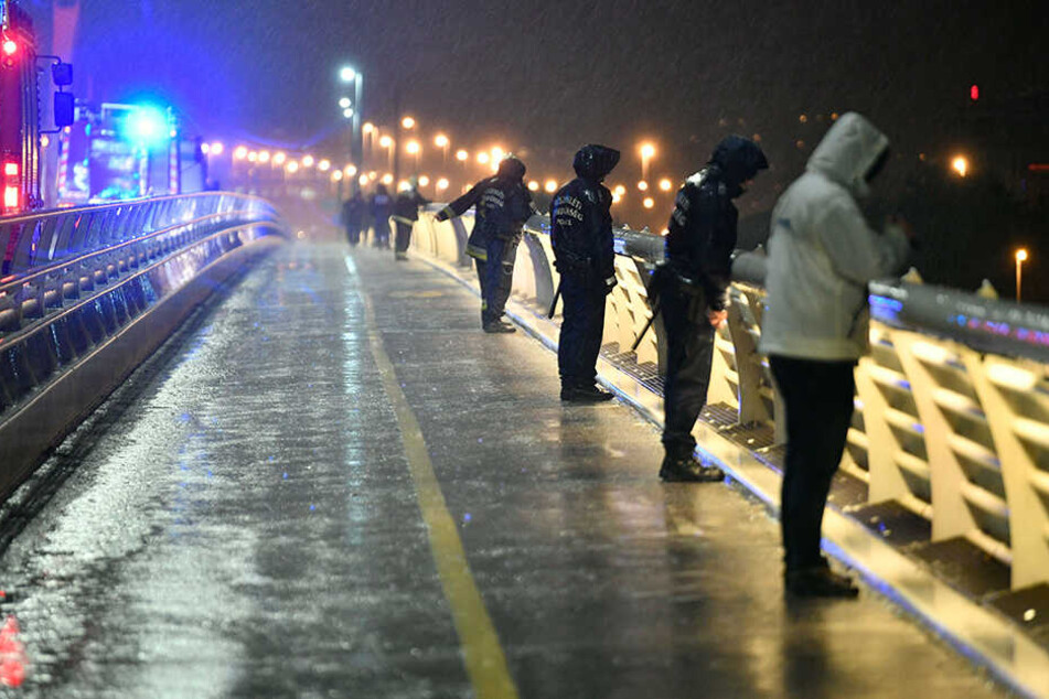 Rettungskräfte und Polizisten inspizieren die Donau von einem Anlegesteg aus.
