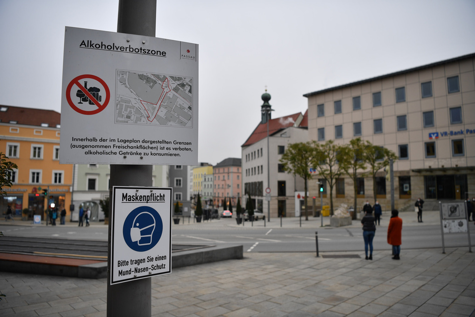 Schilder weisen am Ludwigsplatz auf die bestehende Alkoholverbotszone und die Maskenpflicht in Passau hin.
