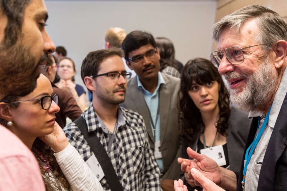 Nobelpreisträger Bill Phillips (rechts im Bild) spricht mit Nachwuchswissenschaftlern während der 66. Lindauer Nobelpreisträgertagung.