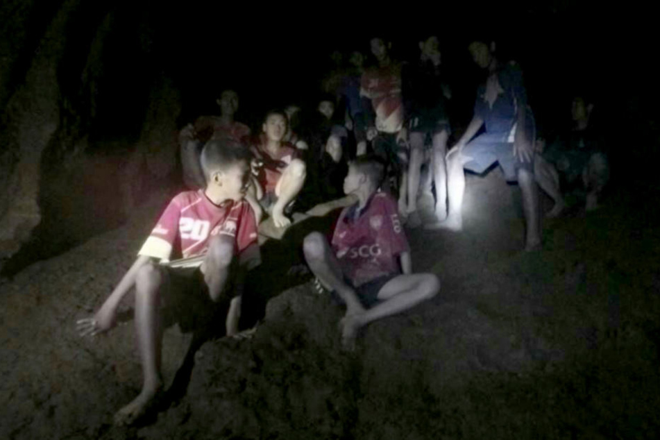 Eine der Thai Navy Seals zur Verfügung gestellte Aufnahme zeigt die vermissten Jugendfußballer und ihren Trainer, nachdem sie in einer Höhle entdeckt wurden.