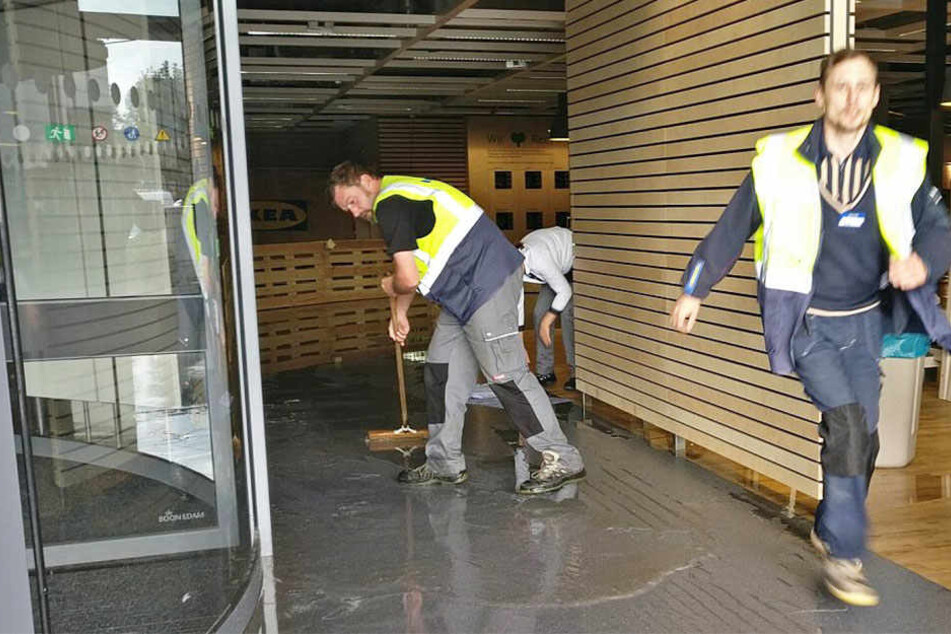 Die Feuerwehrleute kämpfen gemeinsam mit Mitarbeitern des Möbelhauses gegen das Wasser an.